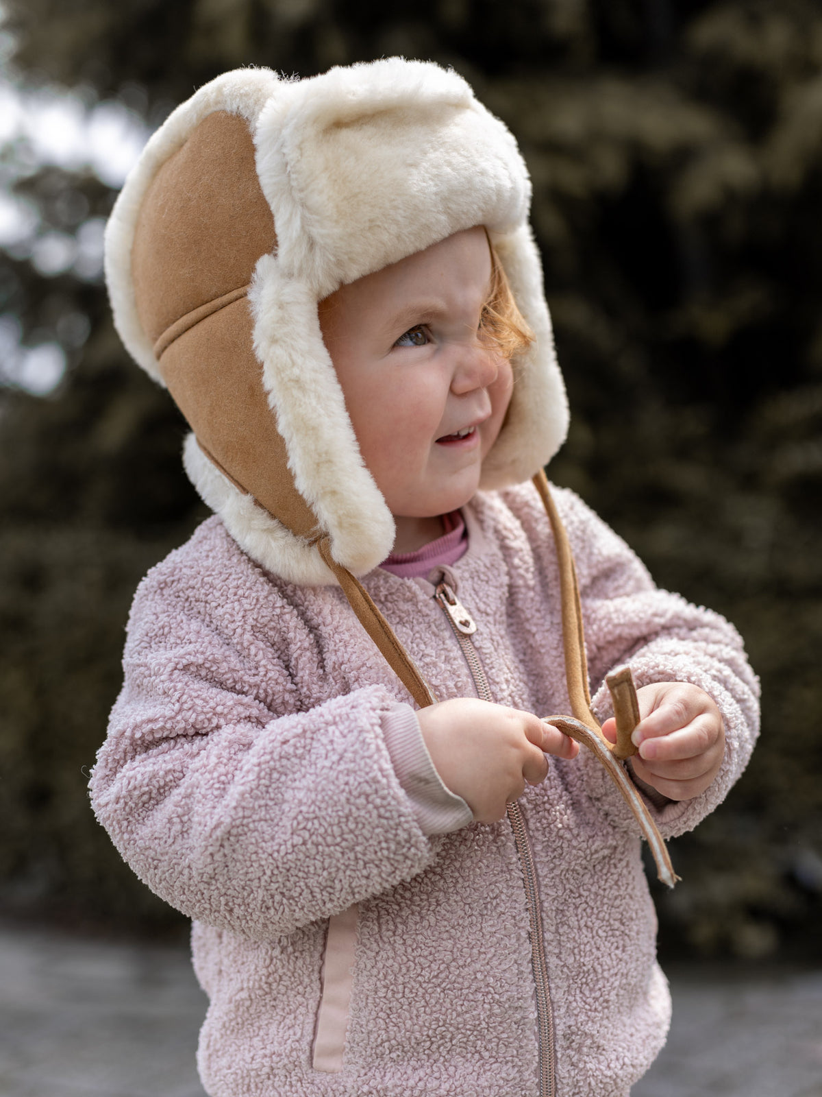 Bonnet aviateur bébé et enfant en peau de mouton camel, porté par une petite fille, cordons noués