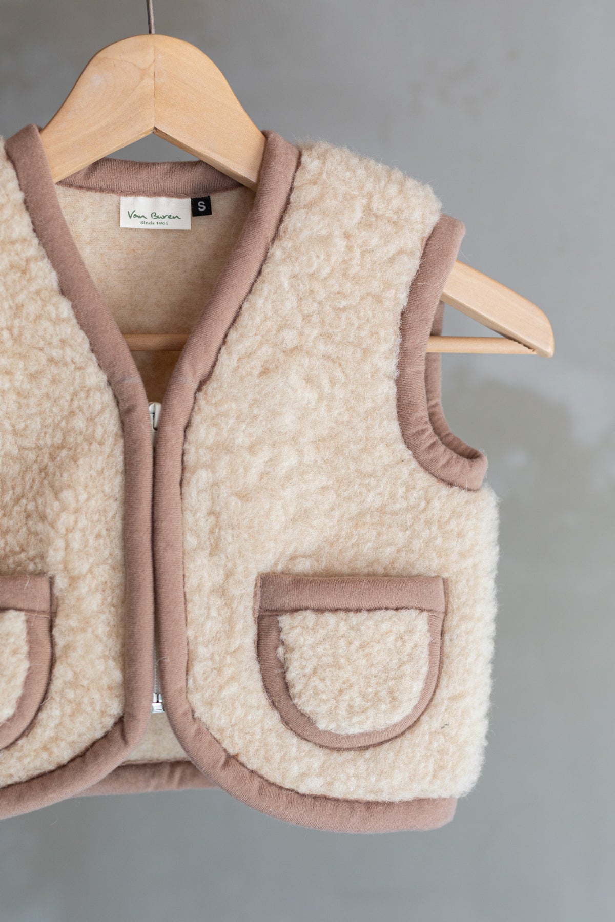 Gilet sans manches en laine pour enfant camel, suspendu à un cintre