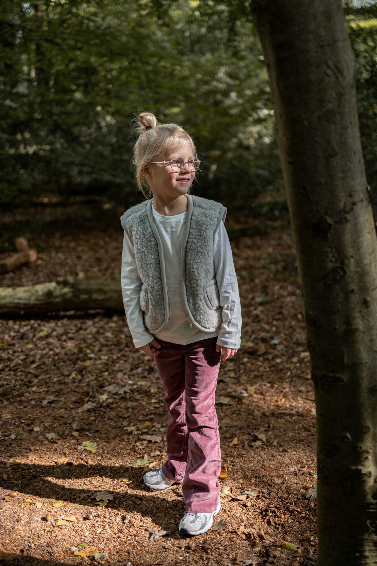 Gilet sans manches en laine pour enfant gris, porté par une petite fille en forêt
