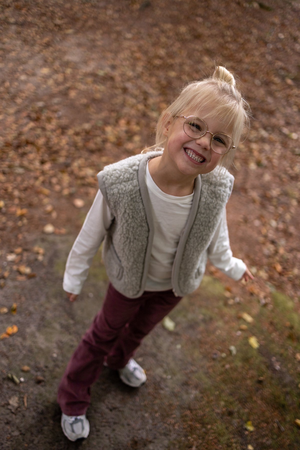 Gilet sans manches en laine pour enfant gris, porté par une enfant qui sourit