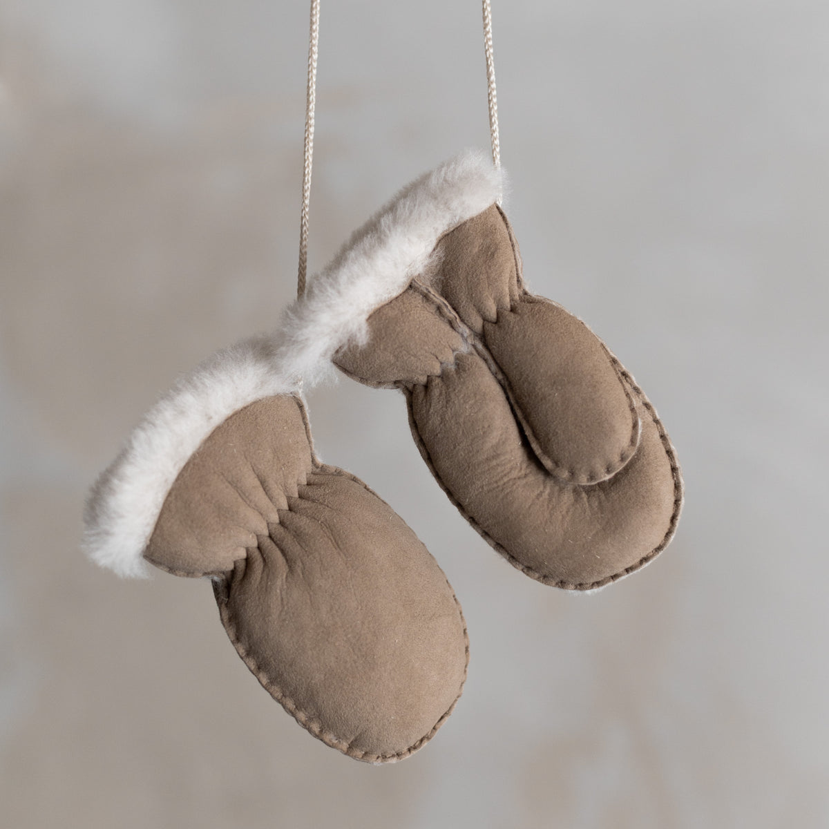 Moufles bébé et enfant en peau d'agneau taupe, paire suspendue par son cordon