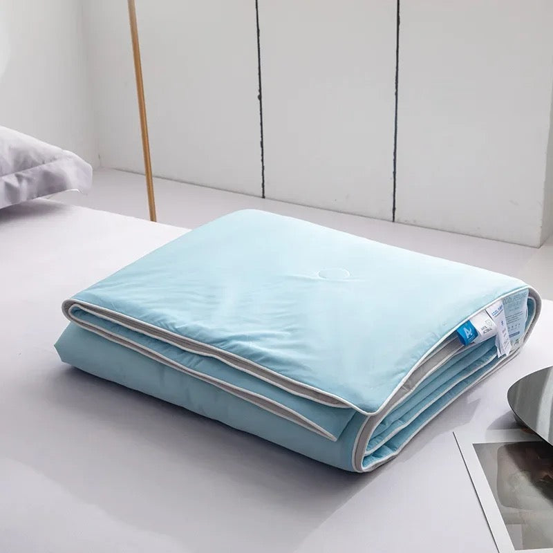 Plaid d'été rafraîchissant bleu plié sur un lit, dans une chambre lumineuse