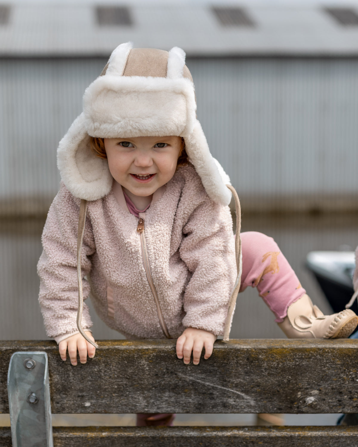 Bonnet aviateur bébé et enfant en peau de mouton taupe, porté par une petite fille en extérieur