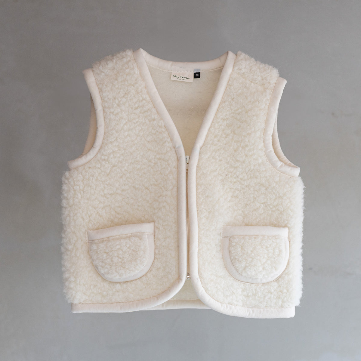 Gilet sans manches en laine pour enfant blanc cassé, vu de face, fermeture éclair et poches